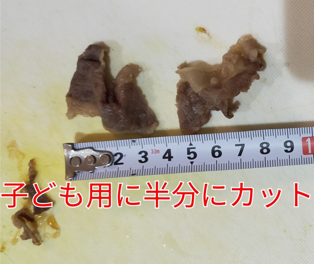 わんまいる美食弁当のすき焼きの牛肉を、子ども用に半分にカットしている画像