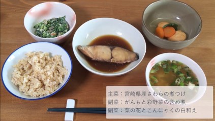 わんまいるの煮魚セット。宮崎県産さわらの煮つけ、がんもと彩野菜の含め煮、菜の花とこんにゃくの白和えが揃った定食風の食事。玄米ご飯と味噌汁はレビュー者が用意したもの。