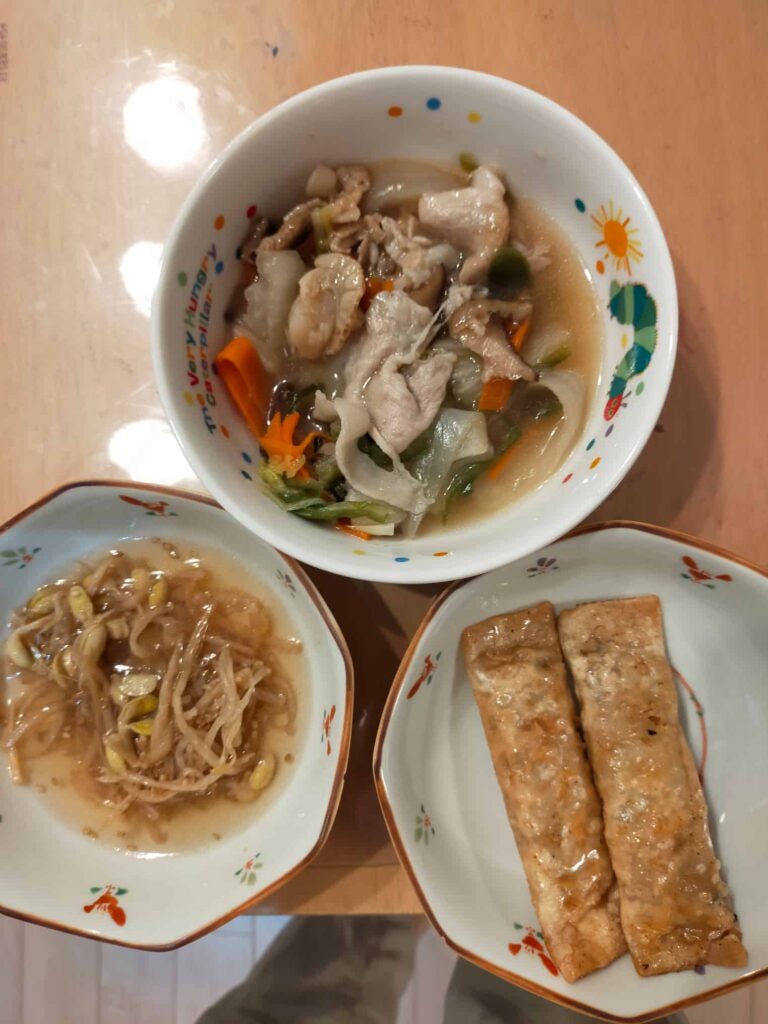 主菜: 石見ポークの八宝菜、副菜: 揚げ春巻きと豆もやしの中華風ナムル。わんまいる健幸ディナーの一食分の盛り付け例