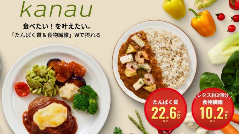 kanau冷凍弁当の商品イメージ。「たんぱく質22.6g以上」と「食物繊維10.2g以上」を1食で摂取可能な冷凍食品。デミグラスハンバーグやシーフードカレーを含むおいしいメニューが紹介されている。背景には新鮮な野菜も配置。